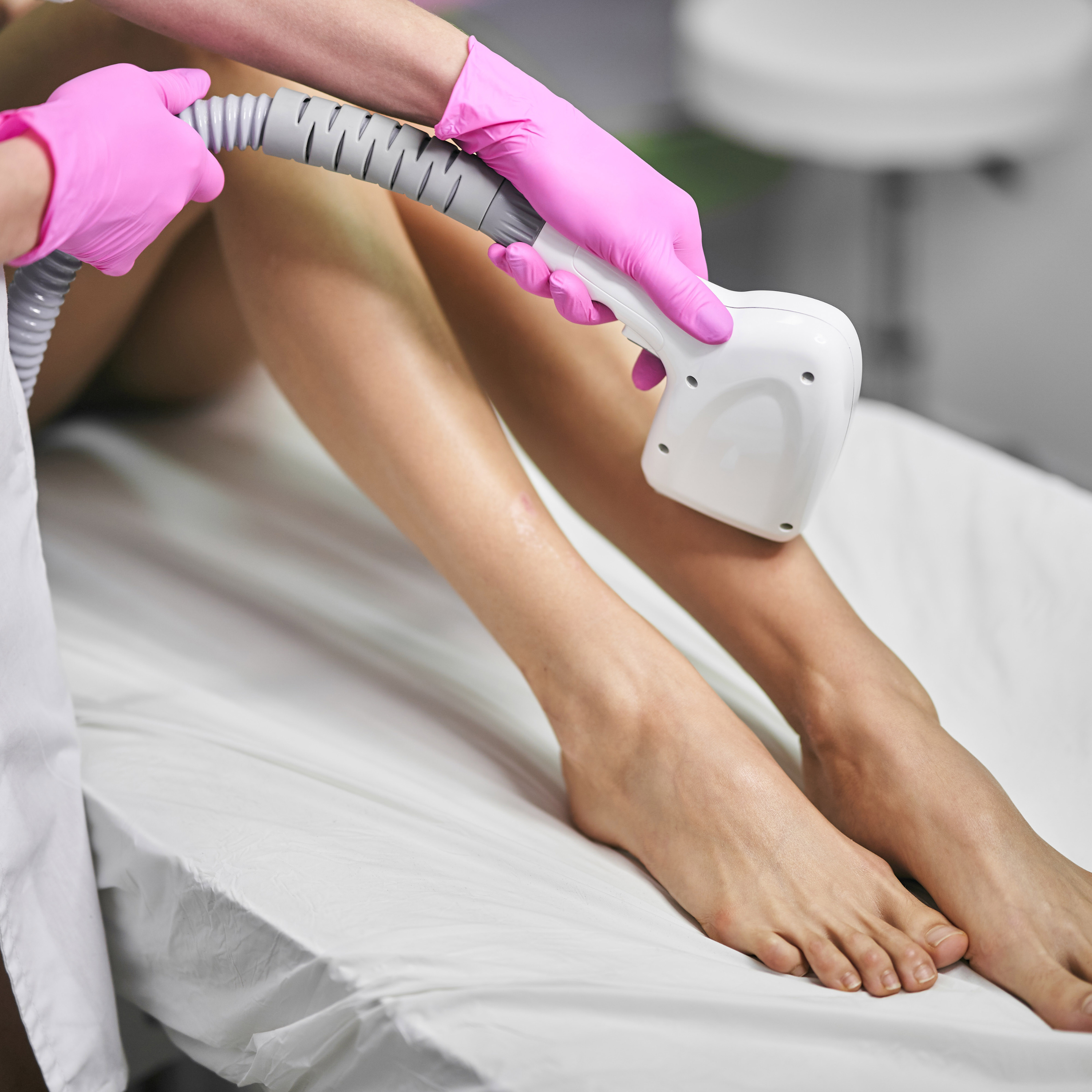 depilacja laserowa nóg w różowych rękawiczkach